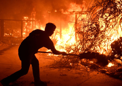 Home owner Will Buckley uses a shovel with dirt to try to stop the flames from from destroying a neighbor's home during the Woolsey Fire in Malibu, California, U.S. November 9, 2018. Photo by REUTERS/Gene Blevins