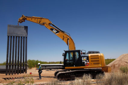 A construction worker stands by heavy machinery carrying a panel of new bollard wall in Santa Teresa, New Mexico, as seen from the Mexican side of the border in San Jeronimo, on the outskirts of Ciudad Juarez, Mexico. Photo by Jose Luis Gonzalez/Reuters