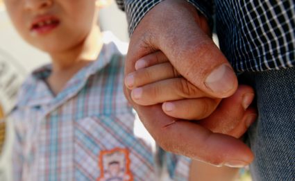 A Salvadoran migrant father holds the hand of his 3-year-old son in Ciudad Juarez, Mexico, in June 2018. Photo by Jose Luis Gonzalez/Reuters