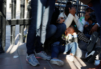 The daughter of Maria Meza, a 40-year-old migrant woman from Honduras, part of a caravan of thousands from Central America trying to reach the United States, sleeps as she waits with her mother sitting at the Otay Mesa port of entry in San Diego to be processed as asylum seeker, as seen from Tijuana, Mexico. Photo by Mohammed Salem/Reuters