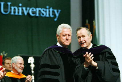Former U.S. Presidents Bill Clinton (L) and George Bush stand on the podium at the Tulane University commencement in New Orleans May 13, 2006. Photo by Alex Brandon/Pool via Reuters