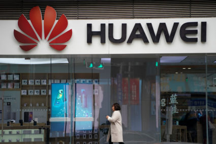 A woman walks by a Huawei logo at a shopping mall in Shanghai, China. Photo by Aly Song/Reuters