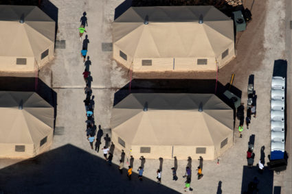Immigrant children are led by staff in single file between tents at a detention facility next to the Mexican border in Tornillo, Texas, in June 2018. Photo By Mike Blake/Reuters