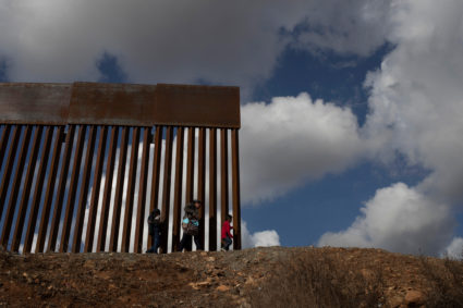 Jessica, a migrant woman from Guatemala seeking asylum, walks to the edge of the border wall before making an unauthorized crossing into the U.S. with her sons Francisco, 5, and Jorge, 9, from the outskirts of Tijuana into San Diego County in December. Photo by Adrees Latif/Reuters