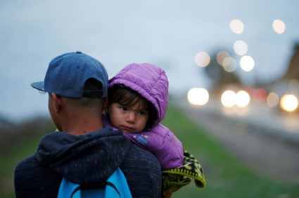Migrants from Honduras, part of a caravan of thousands from Central America trying to reach the United States, walk near the border fence before crossing it illegally from Mexico into the U.S., in Tijuana, Mexico. Photo by Mohammed Salem/Reuters