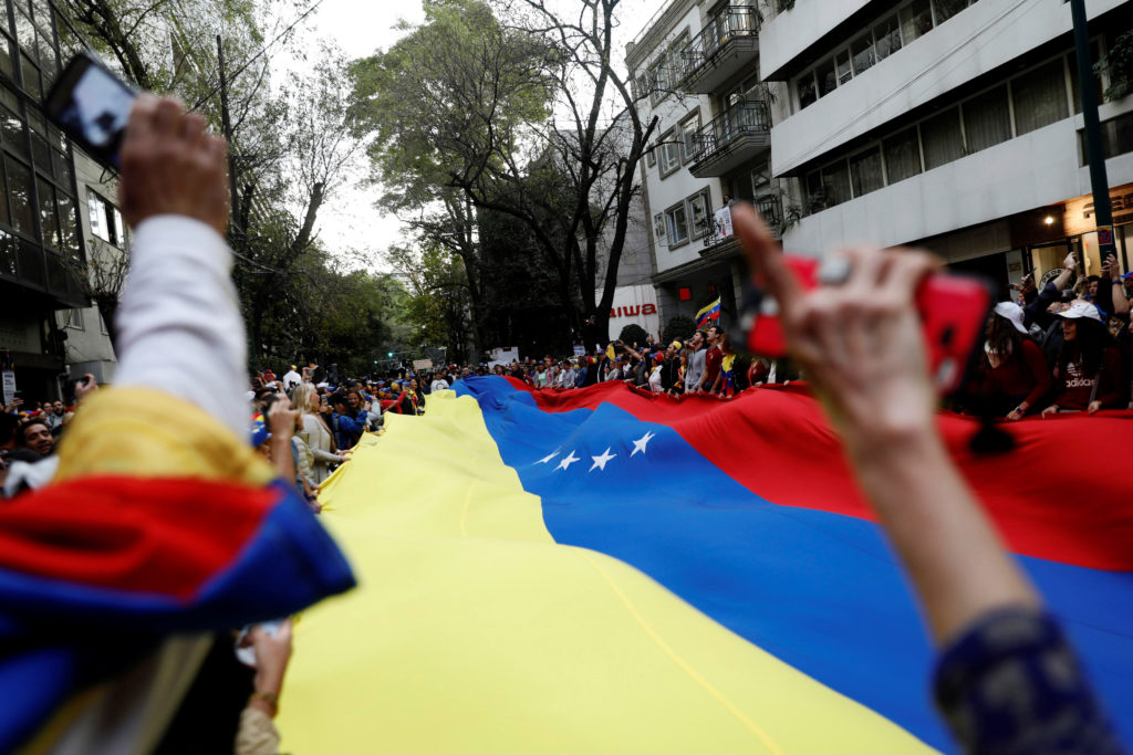 People hold a Venezuelan flag as they gather in support of Venezuela's opposition leader Juan Guaido outside the Embassy o...