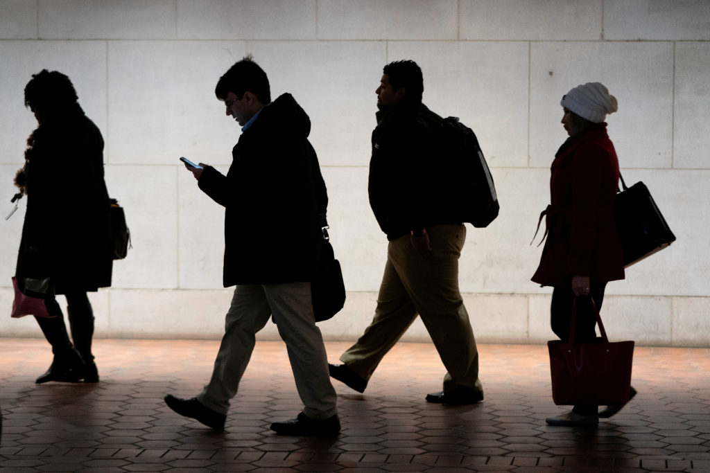 Commuters walk from the Federal Triangle Metro station after the U.S. government reopened with about 800,000 federal worke...