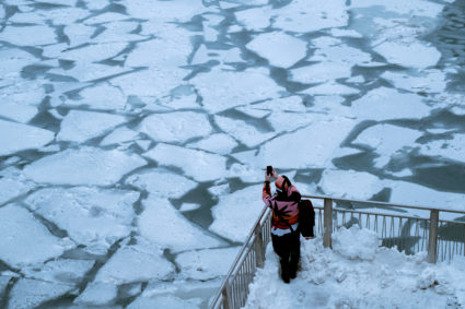 A pedestrian stops to take a photo by Chicago River, as bitter cold phenomenon called the polar vortex has descended on much of the central and eastern United States, in Chicago, Illinois. Photo by Pinar Istek/Reuters