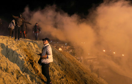Migrants, part of a caravan of thousands from Central America trying to reach the United States, react after U.S. Customs and Border Protection (CBP) throw tear gas to the Mexican side of the fence as they prepared to cross it illegally, in Tijuana, Mexico, January 1, 2019. REUTERS/Mohammed Salem - RC17C4EC1140