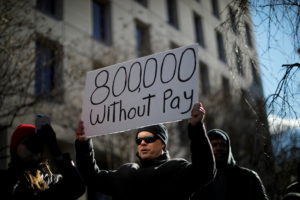 FILE PHOTO: A demonstrator holds a sign, signifying hundreds of thousands of federal employees who won’t be receiving their paychecks as a result of the partial government shutdown, during a “Rally to End the Shutdown” in Washington, U.S., Jan. 10, 2019. Photo by Carlos Barria/Reuters/File Photo