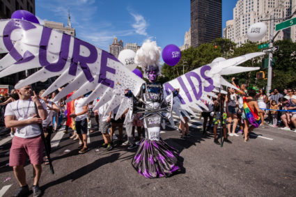 New York City Heritage of Pride March filled Fifth Avenue for hours with groups from the LGBT community and it's supporters. Marchers from the Research Foundation to Cure Aids are lead by a tall man in purple facepaint and with white wings that span two lanes of the street. (Photo by: Ed Lefkowicz /VW Pics/UIG via Getty Images)