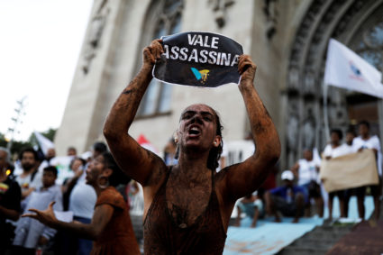 An activist covered in mud, holds a sign reading " VALE SA, Killer !" during a protest against the Brazilian mining company Vale SA, in front of the Se Cathedral in Sao Paulo, Brazil, February 1, 2019. Photo by Nacho Doce/Reuters