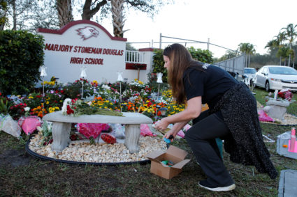 Suzanne Devine Clark places items on a memorial on the one year anniversary of the shooting which claimed 17 lives at Marjory Stoneman Douglas High School in Parkland, Florida. Photo by Joe Skipper/Reuters
