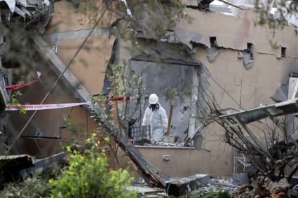 A police sapper inspects a damaged house that was hit by a rocket north of Tel Aviv, Israel. Photo by Ammar Awad/Reuters