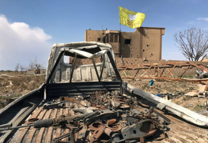 A Syrian Democratic Forces flag flutters on a damaged building in the village of Baghouz, Deir Al Zor province, Syria, March 23, 2019. Photo by Stringer/Reuters