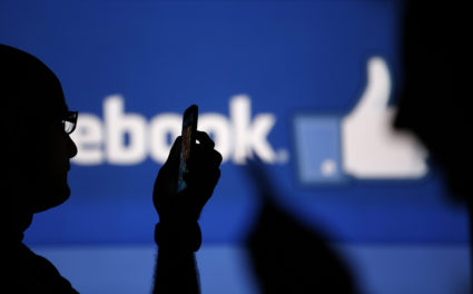 Men are silhouetted against a video screen with an Facebook logo as he poses with an Nokia Lumia 820 and Samsung Galaxy S4 in this photo illustration. Facebook is facing charges that its targeted advertising platform violates the Fair Housing Act. Photo by Dado Ruvic/Reuters