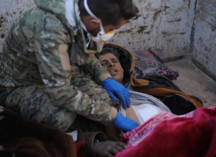 A member of the Syrian Democratic Forces (SDF) delivers care to Hareth Najem, an Iraqi orphan, near the village of Baghouz, Deir Al Zor province, Syria March 1, 2019. Picture taken March 1, 2019. Photo by Rodi Said/Reuters