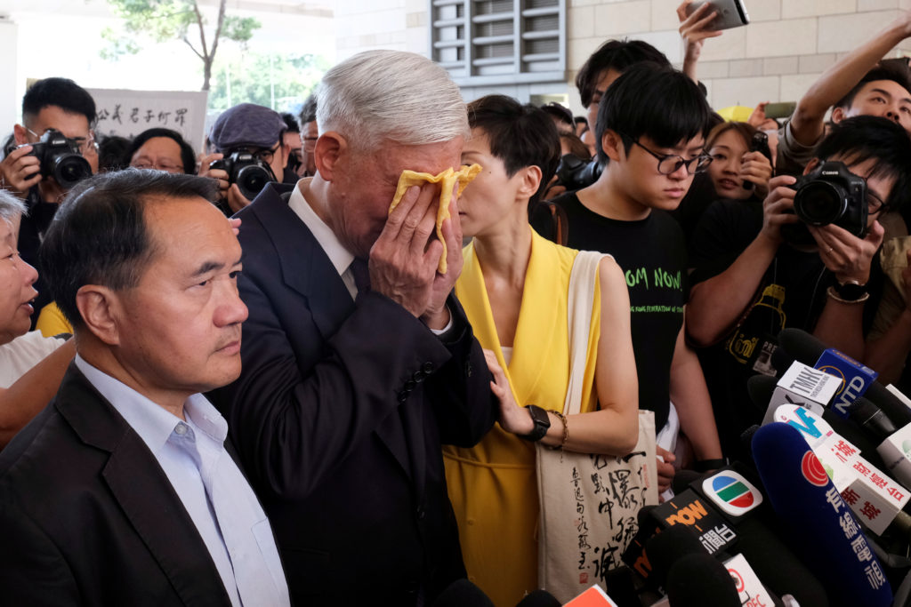 Occupy Central pro-democracy movement founder Chu Yiu-ming (center) cries as he speaks to the media after getting his susp...
