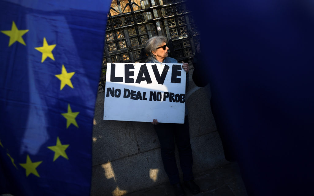 A pro-Brexit supporter is surrounded by EU flags outside the Houses of Parliament in London on April 1, 2019. Photo by Dyl...