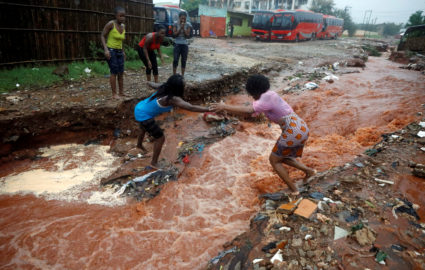 A woman crosses a flooded street in the aftermath of Cyclone Kenneth in Pemba, Mozambique, April 28, 2019. Photo by Mike Hutchings/Reuters