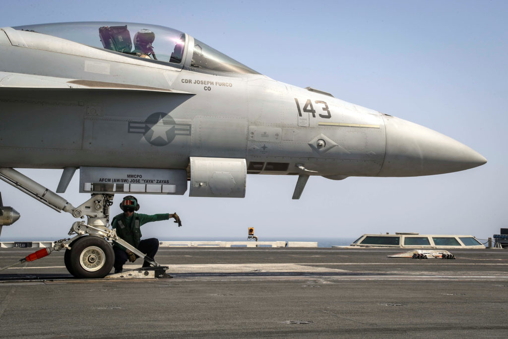 A flight deck crew ensures an F/A-18E Super Hornet is seated in the catapult shuttle on the flight deck of the aircraft ca...