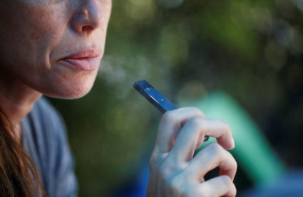 A woman smokes a Juul e-cigarette in this posed picture. Photo by Ronen Zvulun/Reuters