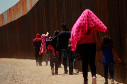 A child drinks a bottle with milk while carried by a woman together with a group of Central American migrants walking next to the U.S.-Mexico border fence after they crossed the borderline in El Paso, Texas, on May 15, 2019. Photo by Jose Luis Gonzalez/Reuters