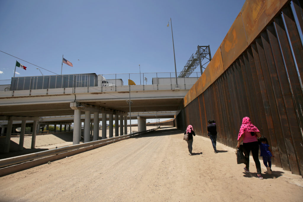 A group of Central American migrants walk next to the U.S.-Mexico border fence after they crossed the borderline in El Pas...