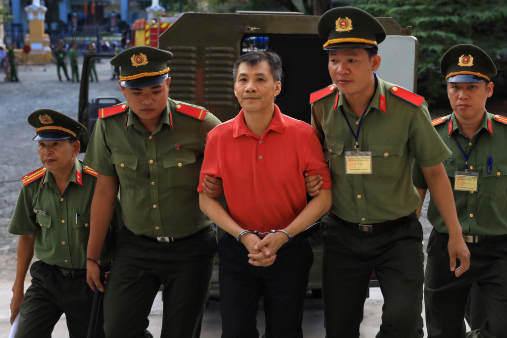 U.S. citizen Michael Nguyen is escorted by policemen before his trial at a court in Ho Chi Minh city, Vietnam on June 24, ...