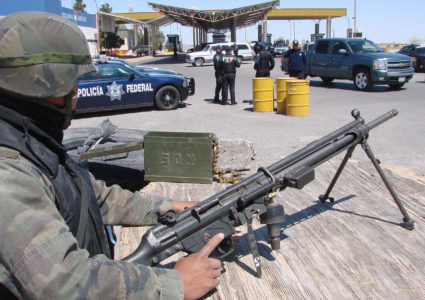 A soldier guards a checkpoint as federal policemen search cars for drugs and weapons at the Cordova-Americas international border crossing bridge in the border city of Ciudad Juarez April 11, 2009. U.S. President Barack Obama will be in Mexico on April 16 and 17, his first visit to the country as President. Picture taken April 11. REUTERS/Alejandro Bringas (MEXICO POLITICS MILITARY) - GM1E54F0QN001