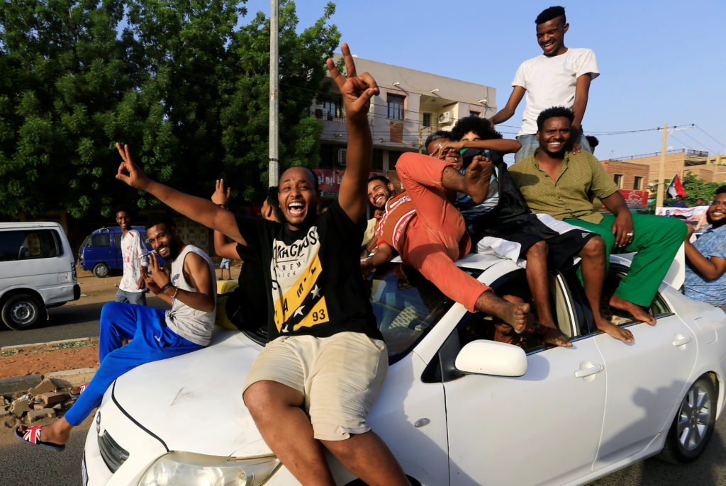Sudanese people ride atop a car chanting slogans as they celebrate, after Sudan's ruling military council and a coalition ...