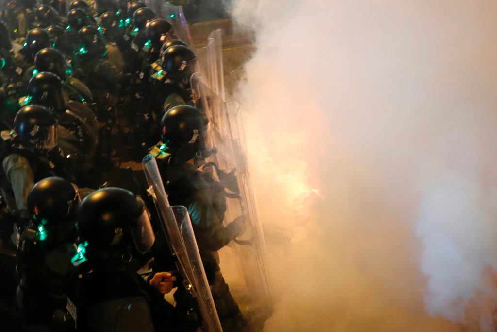 Riot police walk amid tear gas as they try to disperse anti-extradition bill demonstrators after a march to call for democ...
