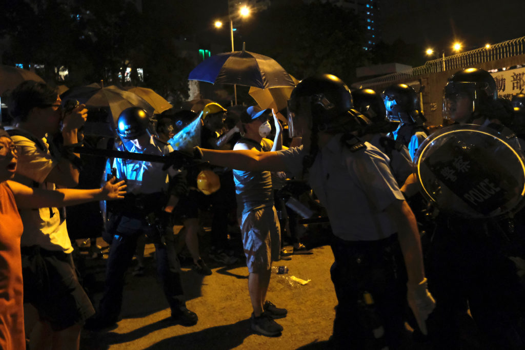 Police officers shout towards anti-extradition bill protesters who surrounded a police station where detained protesters a...