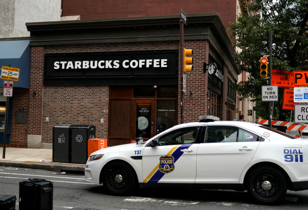 A police officer drives past the center city Starbucks, where two black men were arrested, as they prepare to close to tra...