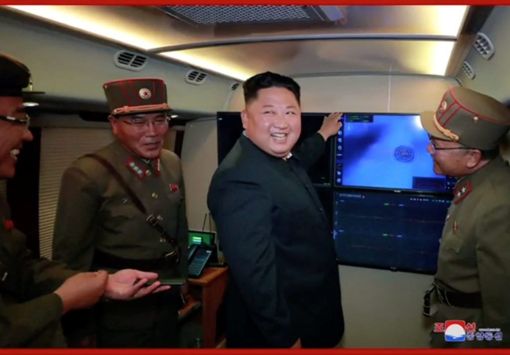 North Korean leader Kim Jong Un smiles with military officials in front of a screen believed to show projectile launch in ...