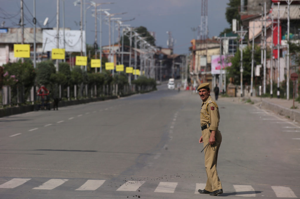 An Indian police officer crosses an empty road during restrictions on Eid-al-Adha after the scrapping of the special const...