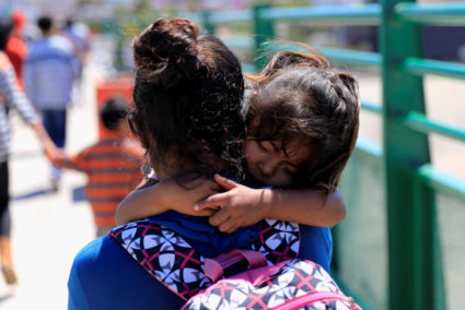 A Central American migrant carries her child just after she was sent to Mexico from the U.S. under the Migrant Protection Protocols (MPP), in Tijuana, Mexico, July 18, 2019. Under new rules proposed by the Trump administration, migrant children could be detained with their families indefinitely. Photo by Carlos Jasso/Reuters
