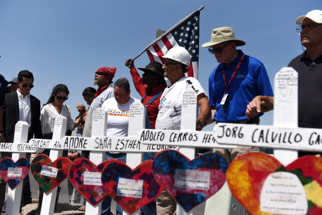 People pray next to a row of crosses representing each of the victims at a growing memorial site two days after a mass sho...