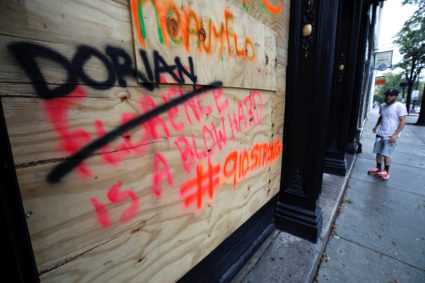 A resident pauses outside a boarded-up business with spray-painted commentary about Hurricane Dorian as the storm approaches, in Wilmington, North Carolina, on September 5, 2019. Photo by Jonathan Drake/Reuters
