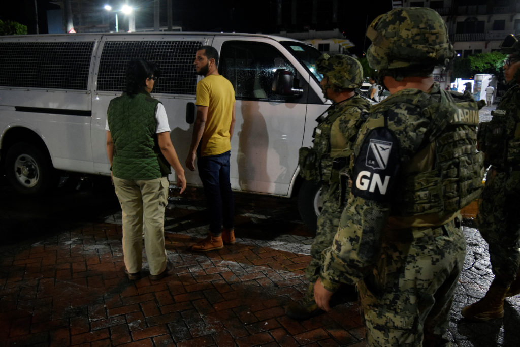 An agent of the National Migration Institute (INM) talks to a migrant detained during an operation in Tapachula, Mexico, S...