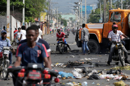 Men riding motorbikes pass on the side of a barricade made of truck and a pole blocking a street in Port-au-Prince, Haiti September 29, 2019. Photo by Andres Martinez Casares/Reuters