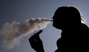 A woman exhales vapour from an e-cigarette outside the offices of British e-cigarette manufacturer Totally Wicked in Blackburn, northern England March 19, 2015. Photo by Phil Noble/Reuters