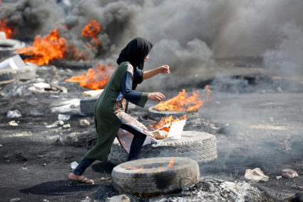 A demonstrator runs between burning tires during a curfew, two days after the nationwide anti-government protests turned violent, in Baghdad, Iraq October 3, 2019. Photo by: Wissm al-Okili /Reuters