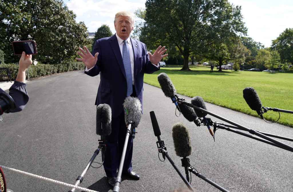 U.S. President Donald Trump answers questions from reporters as he heads to the Marine One helicopter to fly to visit inju...