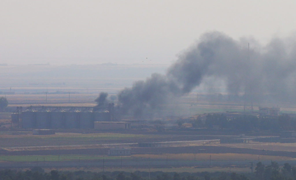 Smoke rises from a building near the Syrian town of Ras al-Ain as seen from the Turkish border town of Ceylanpinar, Sanliu...