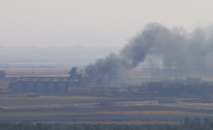 Smoke rises from a building near the Syrian town of Ras al-Ain as seen from the Turkish border town of Ceylanpinar, Sanliurfa province, Turkey, October 18, 2019. Photo by Stoyan Nenov/Reuters