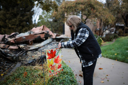FILE PHOTO: Gerryann Wulbern rehangs a welcome sign she found unburned on her lawn after returning to her home for the first time since the Camp Fire devastated the area in Paradise, California, U.S. November 22, 2018. Photo by Elijah Nouvelage/Reuters