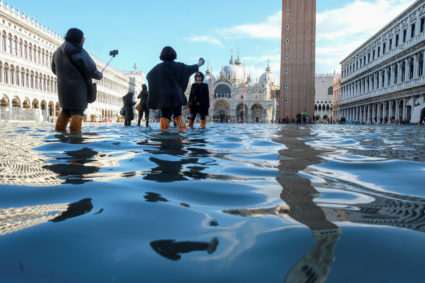 Tourists take pictures in the flooded St. Mark's Square during a period of seasonal high water in Venice, Italy, November 14, 2019. Photo by Manuel Silvestri/Reuters.