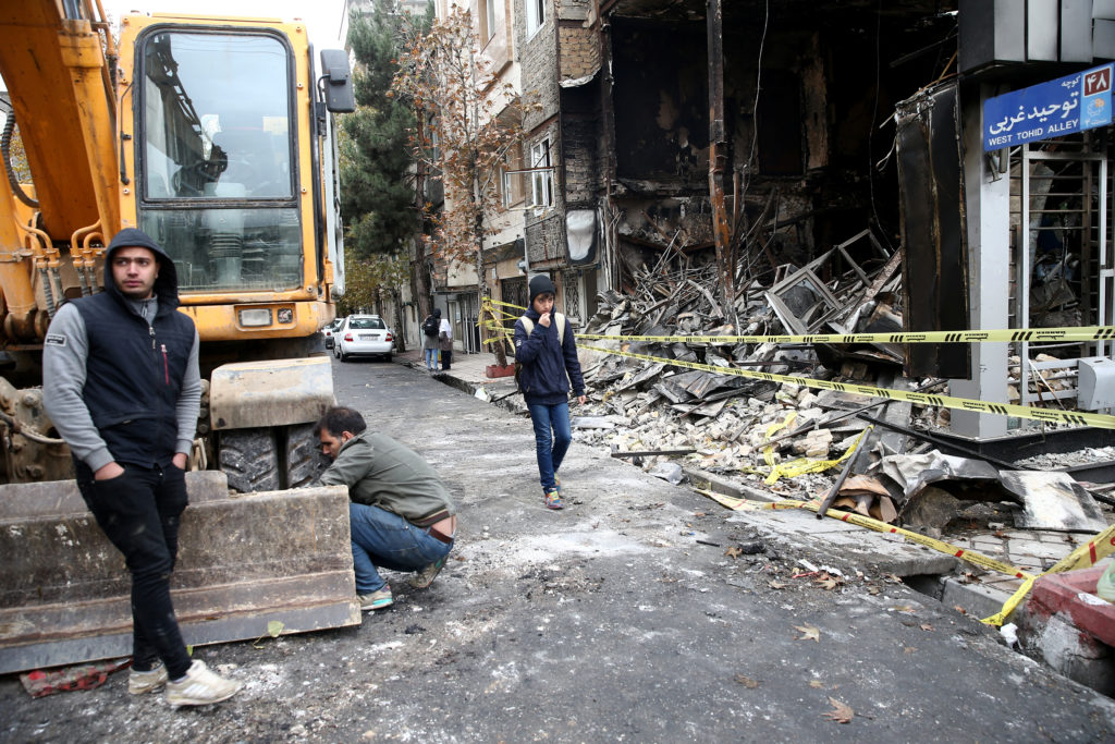 People walk near a burnt bank, after protests against increased fuel prices, in Tehran, Iran November 20, 2019. Picture ta...