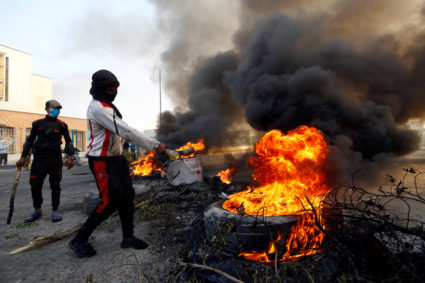 A protester pours fuel on a tire to burn it as he blocks a street during ongoing anti-government protests in Najaf, Iraq November 27, 2019. REUTERS/Alaa al-Marjani